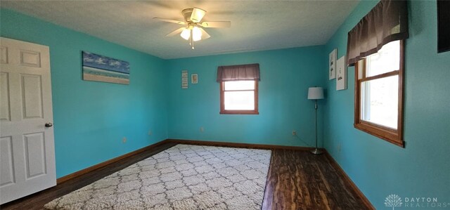 unfurnished room with wood finished floors, a ceiling fan, and baseboards