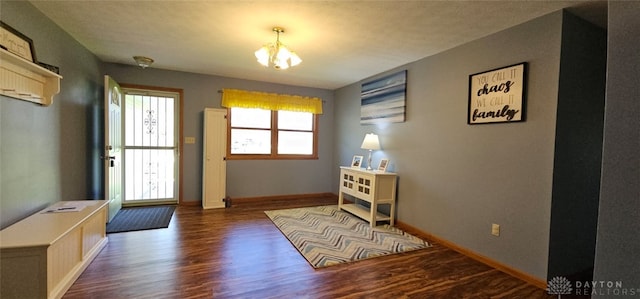 doorway with wood finished floors, a notable chandelier, and baseboards