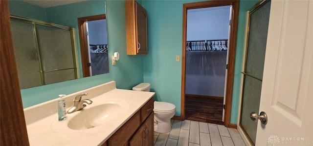 full bathroom featuring vanity, toilet, a shower with shower door, baseboards, and wood finished floors