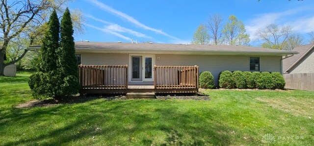 rear view of property featuring a lawn, fence, and a wooden deck