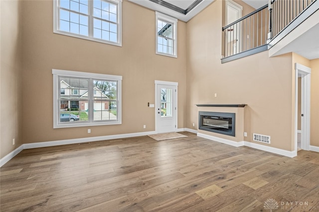 unfurnished living room featuring hardwood / wood-style flooring and a high ceiling