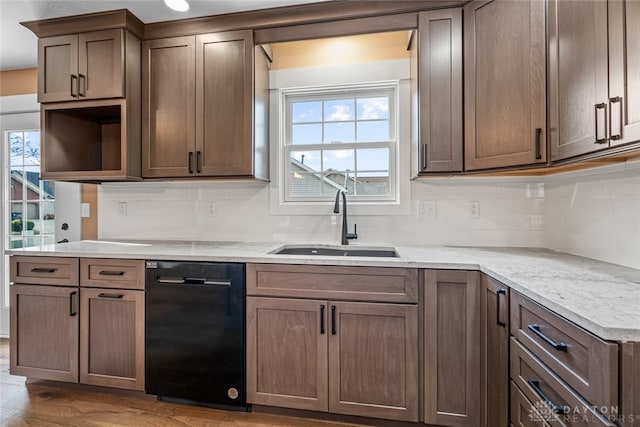 kitchen featuring light stone countertops, sink, dark wood-type flooring, black dishwasher, and decorative backsplash