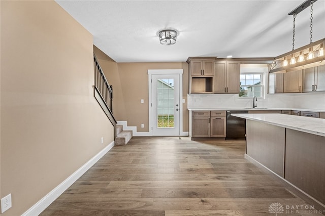 kitchen with pendant lighting, hardwood / wood-style flooring, light stone countertops, black dishwasher, and tasteful backsplash