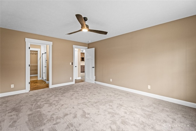 unfurnished bedroom featuring carpet flooring, a closet, a spacious closet, and ceiling fan