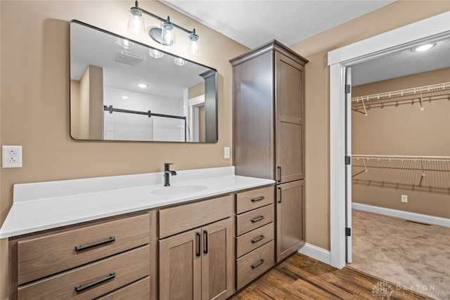 bathroom featuring a textured ceiling, vanity, wood-type flooring, and a shower with door