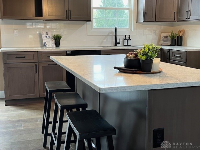 kitchen featuring a breakfast bar area, backsplash, sink, and light wood-type flooring