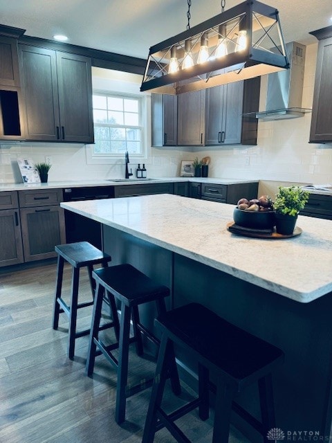 kitchen with hardwood / wood-style flooring, hanging light fixtures, a breakfast bar area, and sink