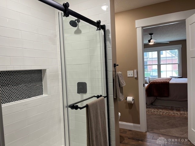 bathroom with a textured ceiling, ceiling fan, hardwood / wood-style floors, toilet, and a shower with shower door