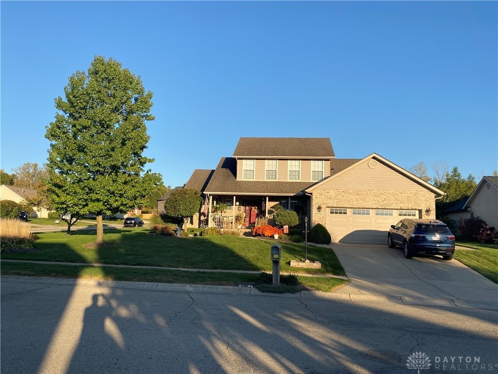 view of front of property featuring covered porch, a front yard, and a garage