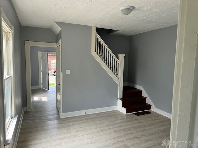 stairway with hardwood / wood-style floors and a textured ceiling