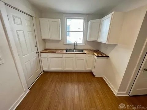 kitchen with white cabinetry, sink, and hardwood / wood-style floors