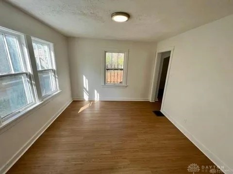 empty room with dark hardwood / wood-style flooring and a textured ceiling