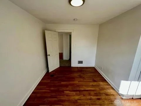 unfurnished room with dark wood-type flooring