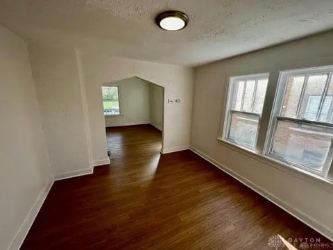 additional living space with a textured ceiling and dark wood-type flooring