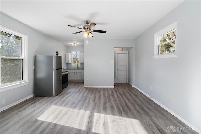 unfurnished living room with light hardwood / wood-style floors, sink, and ceiling fan