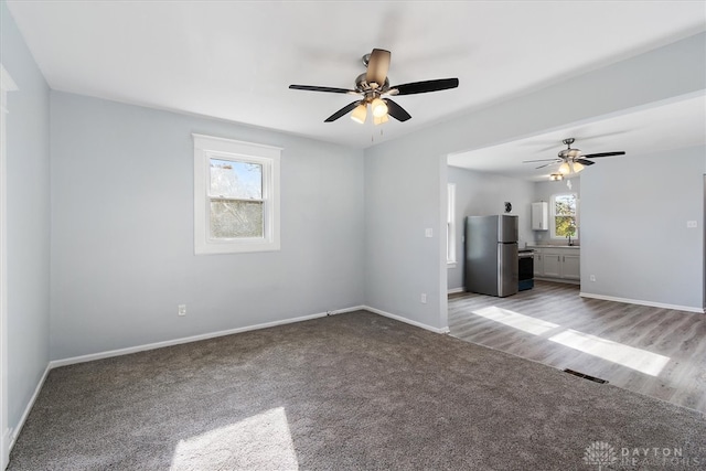 empty room with ceiling fan, a healthy amount of sunlight, and light hardwood / wood-style flooring