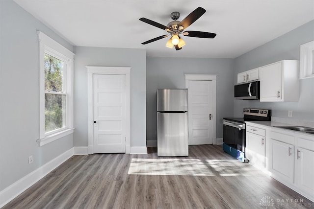 kitchen featuring light hardwood / wood-style floors, sink, appliances with stainless steel finishes, ceiling fan, and white cabinets