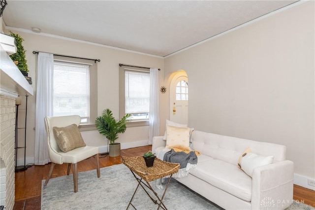 sitting room with hardwood / wood-style floors, a brick fireplace, and crown molding