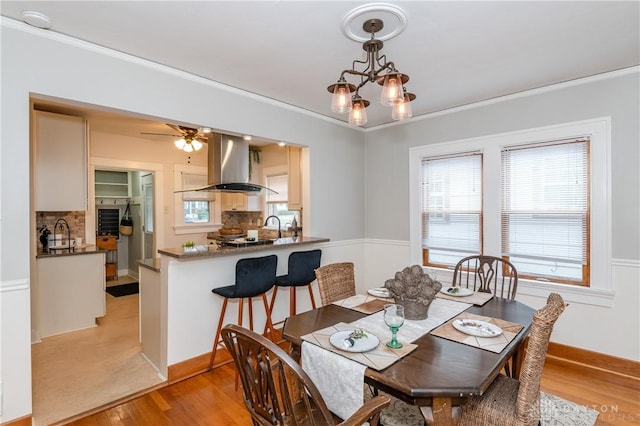 dining area with light hardwood / wood-style flooring, a healthy amount of sunlight, and ornamental molding