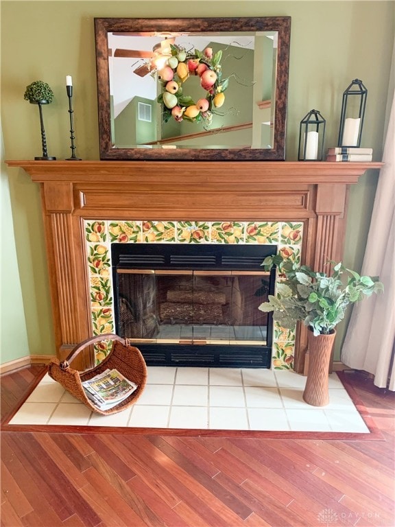 details with hardwood / wood-style flooring and a tiled fireplace