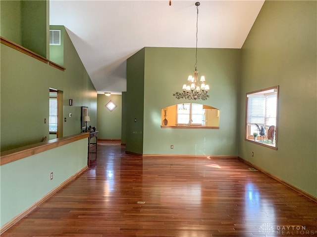 empty room with dark hardwood / wood-style flooring, high vaulted ceiling, and an inviting chandelier