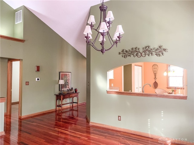 living room with a towering ceiling, hardwood / wood-style flooring, and an inviting chandelier