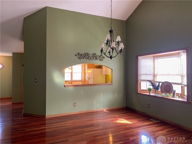 spare room featuring a chandelier, hardwood / wood-style floors, and high vaulted ceiling