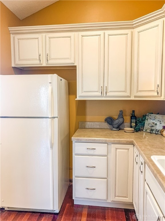 kitchen featuring white fridge, vaulted ceiling, and dark wood-type flooring