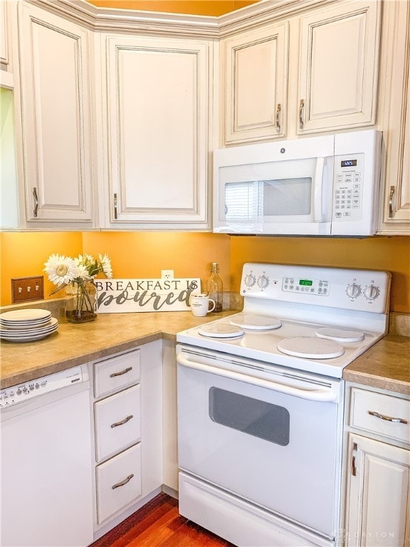 kitchen featuring hardwood / wood-style floors, white appliances, and cream cabinetry