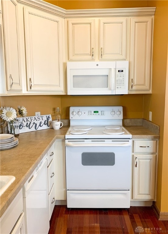 kitchen with cream cabinetry, dark hardwood / wood-style floors, and white appliances