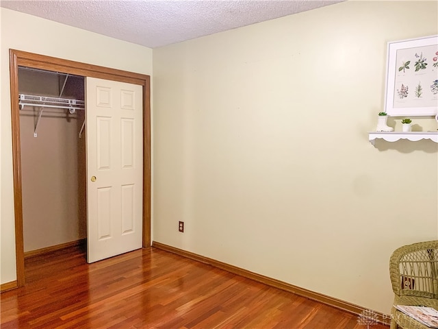 unfurnished bedroom with a closet, a textured ceiling, and hardwood / wood-style flooring