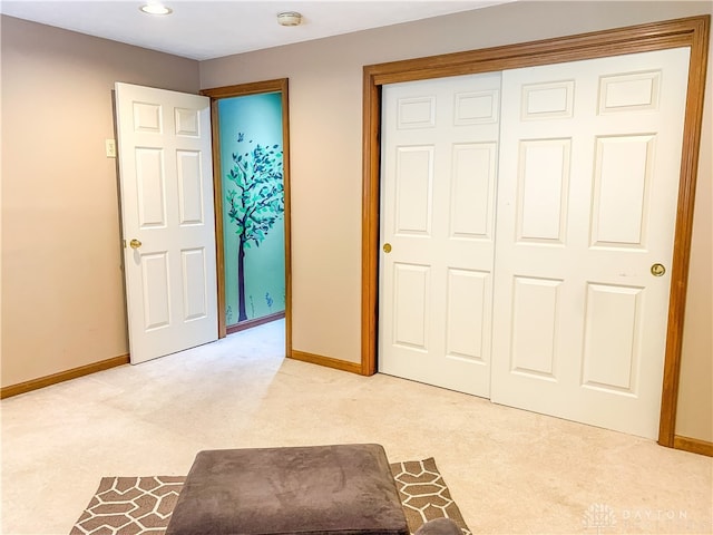 unfurnished bedroom featuring light carpet and a closet