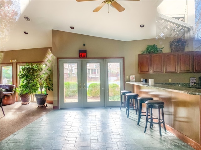 kitchen featuring a kitchen bar, french doors, light colored carpet, ceiling fan, and lofted ceiling