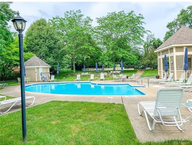 view of pool with a lawn, an outbuilding, and a patio