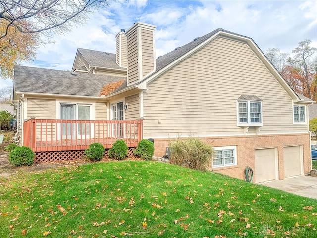 rear view of house with a yard, a deck, and a garage