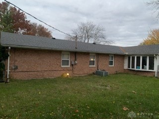 rear view of property with a lawn and central air condition unit