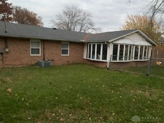 rear view of property featuring a yard and cooling unit