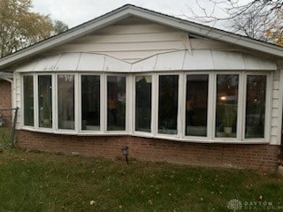 view of side of property with a sunroom and a lawn