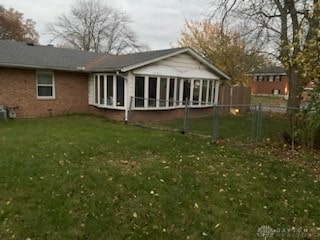 rear view of house featuring a yard and a sunroom