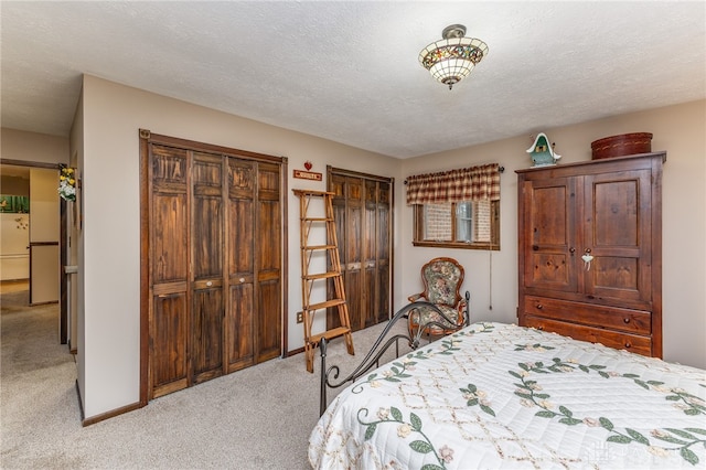 unfurnished bedroom featuring multiple closets, light carpet, and a textured ceiling