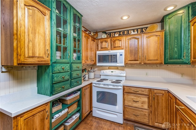 kitchen with a textured ceiling, dark hardwood / wood-style floors, and white appliances