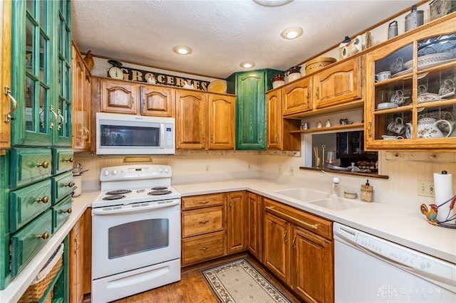 kitchen with a textured ceiling, white appliances, dark hardwood / wood-style flooring, and sink