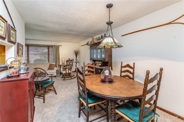 dining room featuring light carpet and a textured ceiling