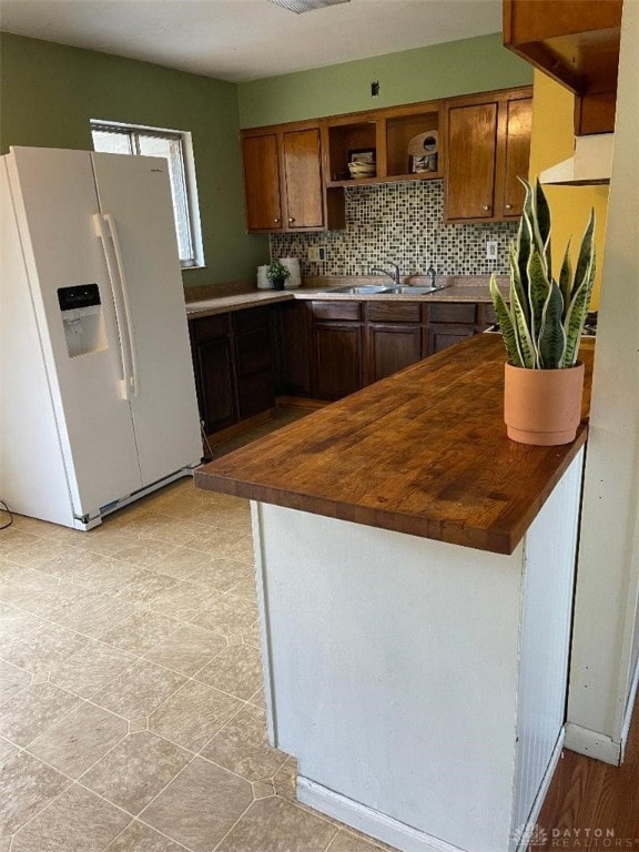 kitchen with tasteful backsplash, white fridge with ice dispenser, wooden counters, and sink