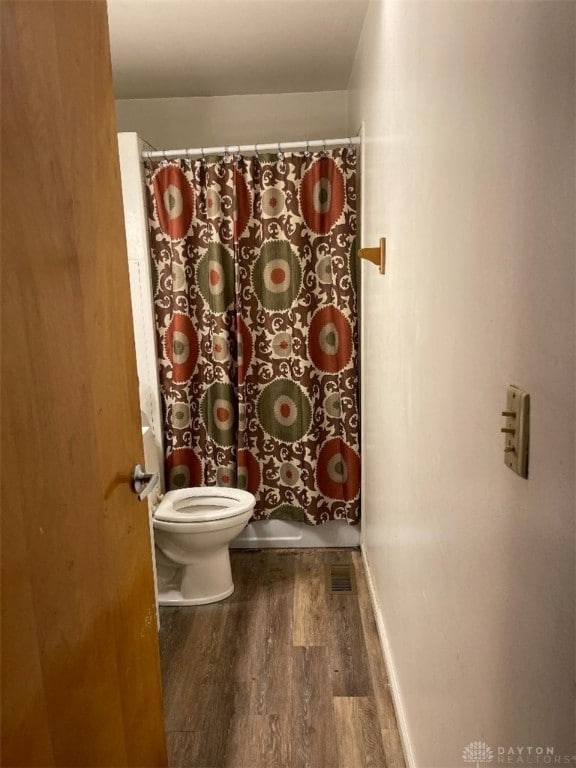 bathroom featuring wood-type flooring, toilet, and walk in shower