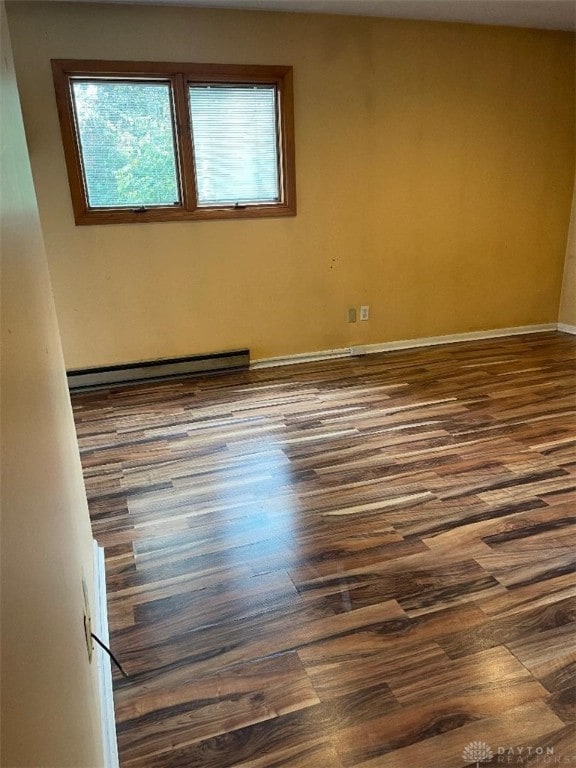 spare room with dark hardwood / wood-style floors and a baseboard radiator