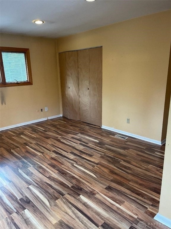 unfurnished bedroom with a closet and dark wood-type flooring