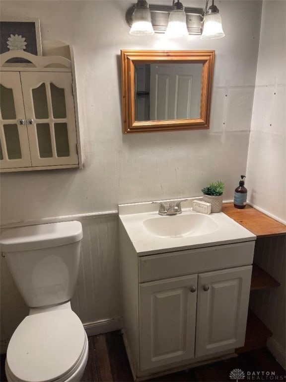 bathroom with vanity, hardwood / wood-style flooring, toilet, and wood walls