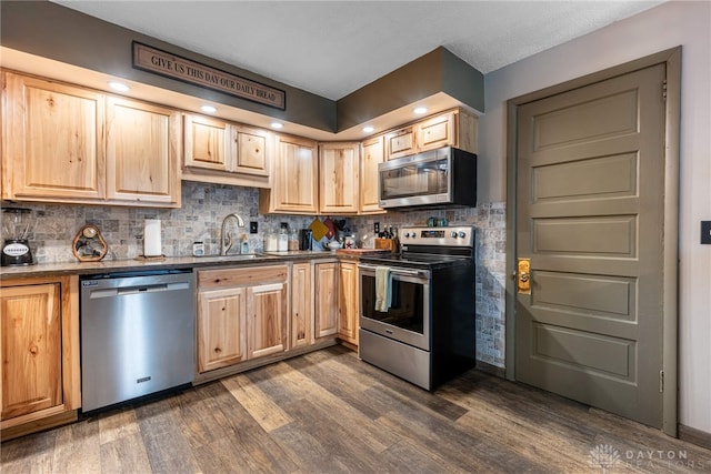 kitchen featuring decorative backsplash, appliances with stainless steel finishes, light brown cabinetry, dark wood-type flooring, and sink