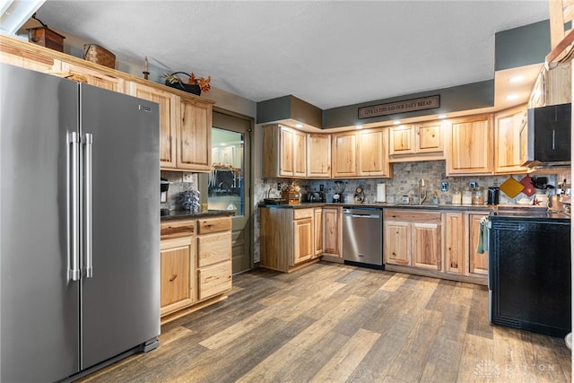 kitchen featuring backsplash, light brown cabinets, wood-type flooring, and appliances with stainless steel finishes